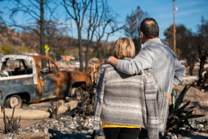 Man and wife looking at home after bushfire