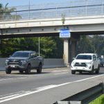 Toyota Hilux woork utes driving side by side down the motorway underneath bridge