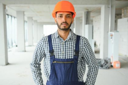 Migrant worker in hard hat posing on construction site