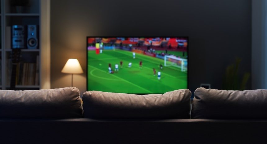Sport playing on television in front of couch in living room