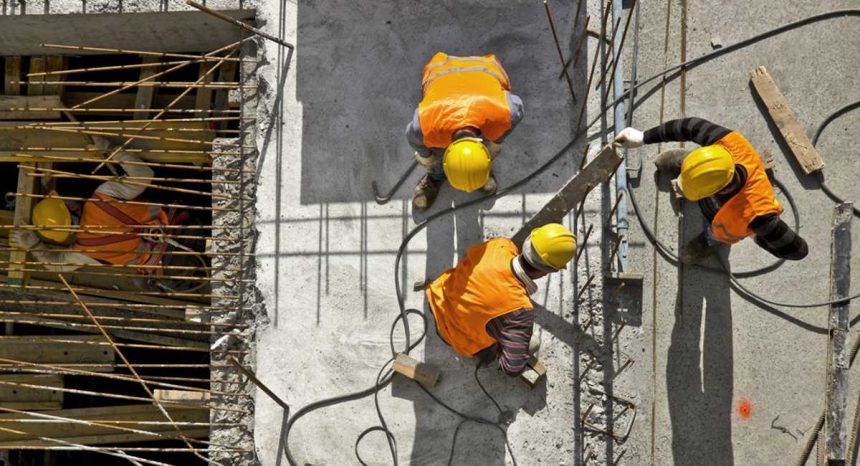 Migrant tradies working on job site in hard hats and high vis