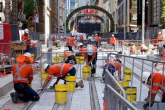 Construction workers paving ground in Sydney CBD for light rail construction project