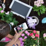 Woman looking at her phone while she's planting flowers in garden