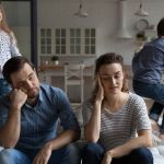 couple on couch sad while kids play around them