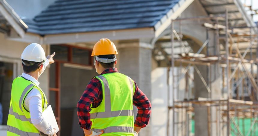 men in high vis and hard hats pointing at home on construction site