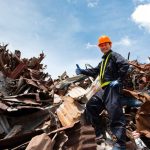 Construction worker standing on pile of recycled metal
