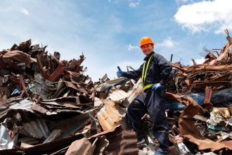 Construction worker standing on pile of recycled metal