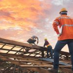 man in hardhat overlooking home construction on timber frame