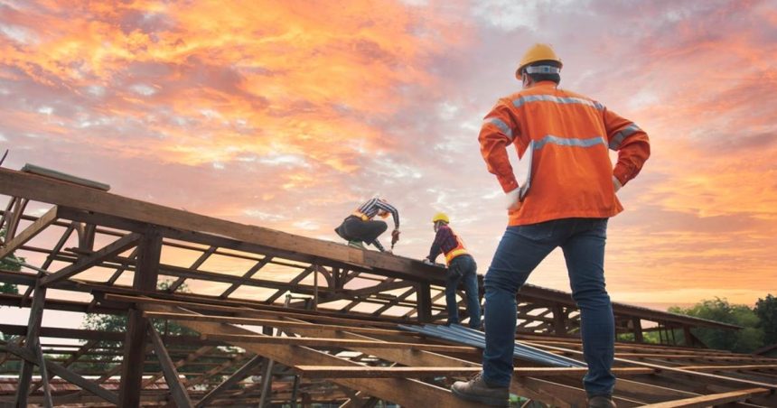 man in hardhat overlooking home construction on timber frame