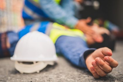 tradie lying on the concrete after a fall while man tries to revive him