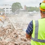 construction worker looks at construction waste on job site