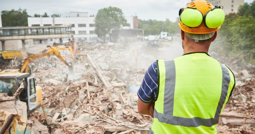 construction worker looks at construction waste on job site