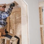 Construction worker drilling into a house under construction