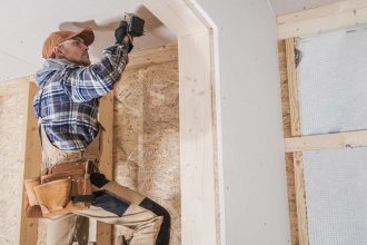 Construction worker drilling into a house under construction