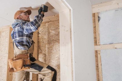 Construction worker drilling into a house under construction