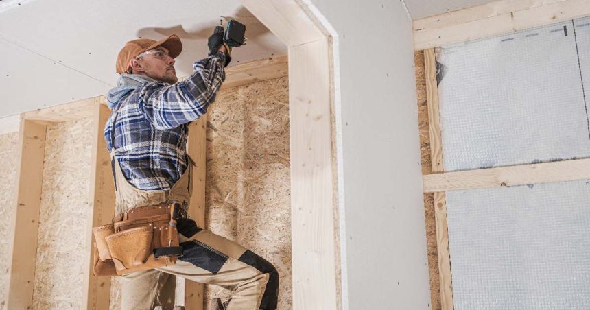 Construction worker drilling into a house under construction