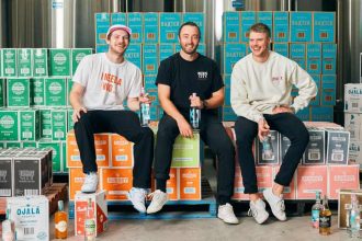 Three men sitting on top of alcohol cartons