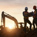 two construction workers hold a map