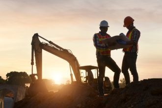 two construction workers hold a map