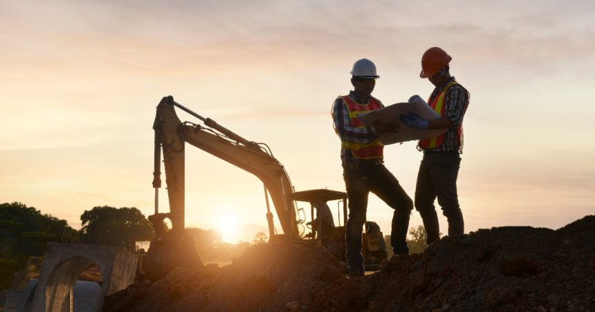 two construction workers hold a map