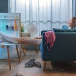 Woman cooling herself down in front of fridge in home