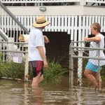 Homeowners talking outside of flood damaged homes