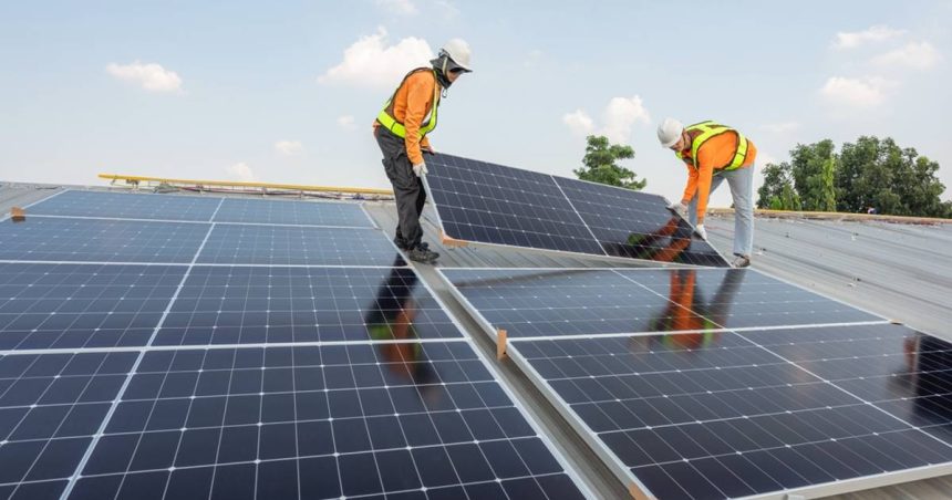 Two workers installing solar panels on rooftop