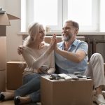 Older home owners sitting amongst moving boxes in new home