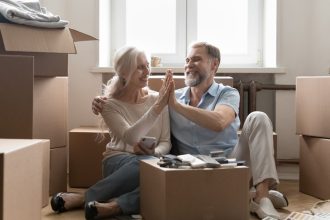 Older home owners sitting amongst moving boxes in new home