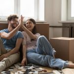 Young homeowners sitting on the floor surrounded by moving boxes