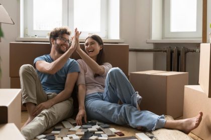 Young homeowners sitting on the floor surrounded by moving boxes