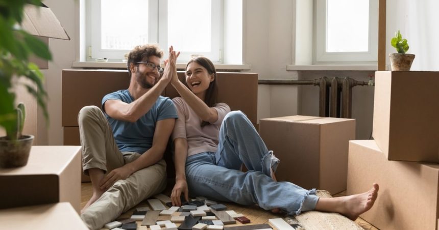 Young homeowners sitting on the floor surrounded by moving boxes