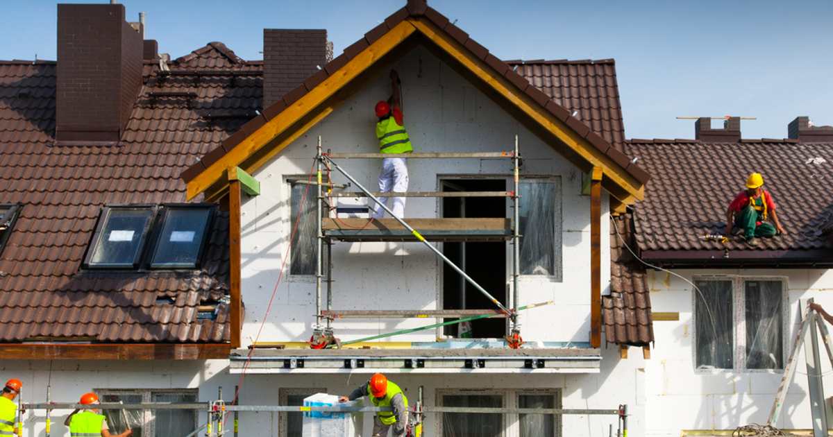 construction workers surrounding house being built