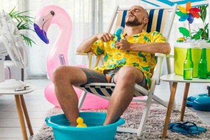 a man feels hot inside his home and attempts to cool down using a fan and paddling pool