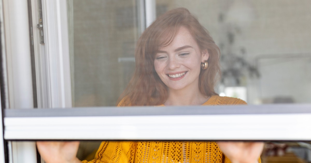 a woman closes fly screen