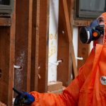 Asbestos removal by man in hazmat suit